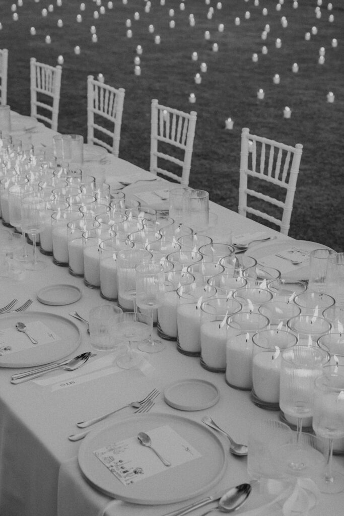 Decoración de evento en Lamarr Alicante con largas mesas iluminadas por cientos de velas blancas, diseño elegante junto a palmeras