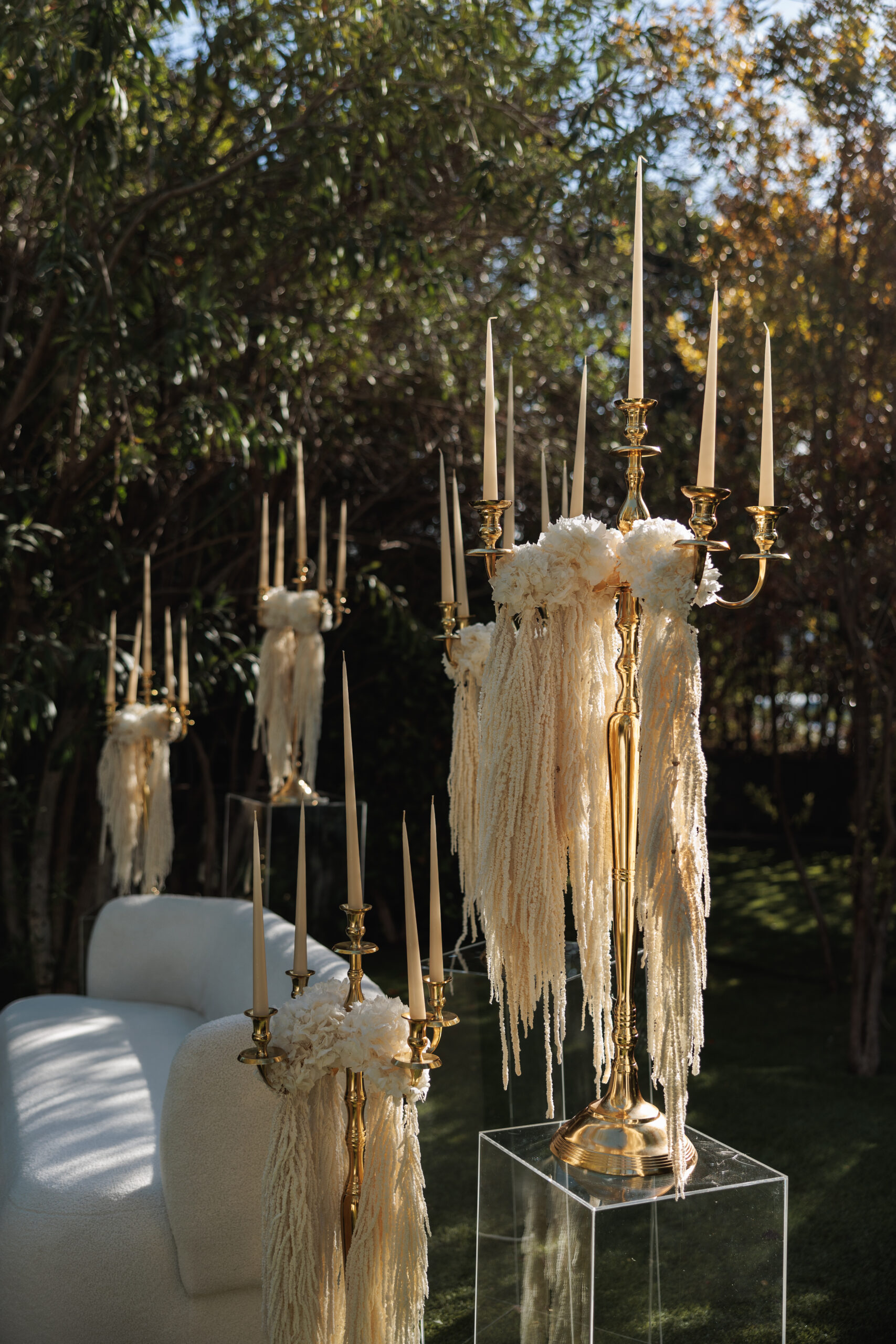 Montaje de evento con alquiler de velas largas, candelabros dorados y decoración con lazos.