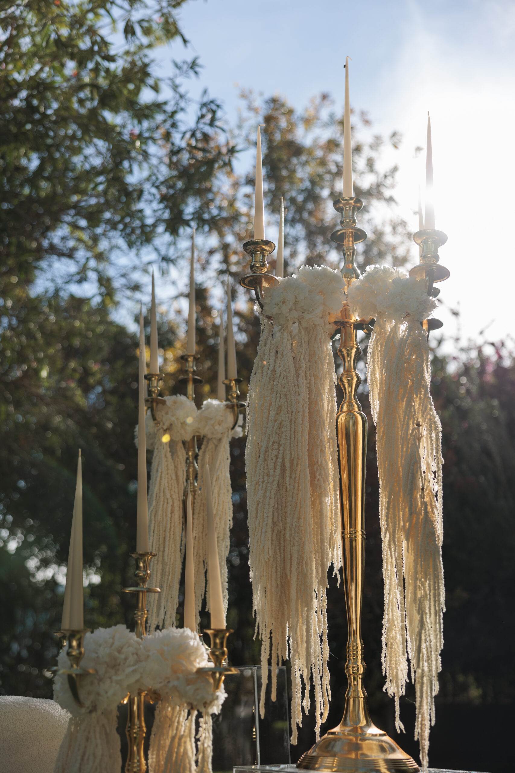 Montaje de evento con alquiler de velas largas, candelabros dorados y decoración con lazos.