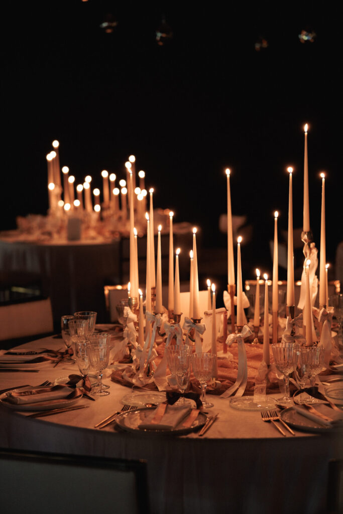 Montaje de evento con alquiler de velas largas, candelabros dorados y decoración con lazos.