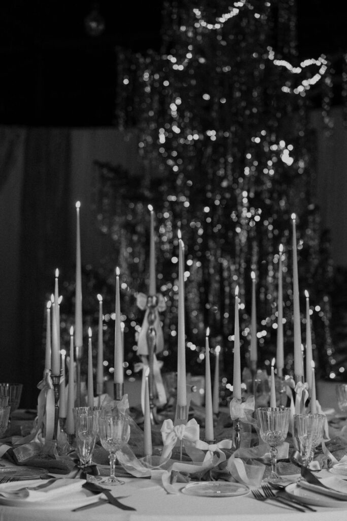 Montaje de evento con alquiler de velas largas, candelabros dorados y decoración con lazos.
