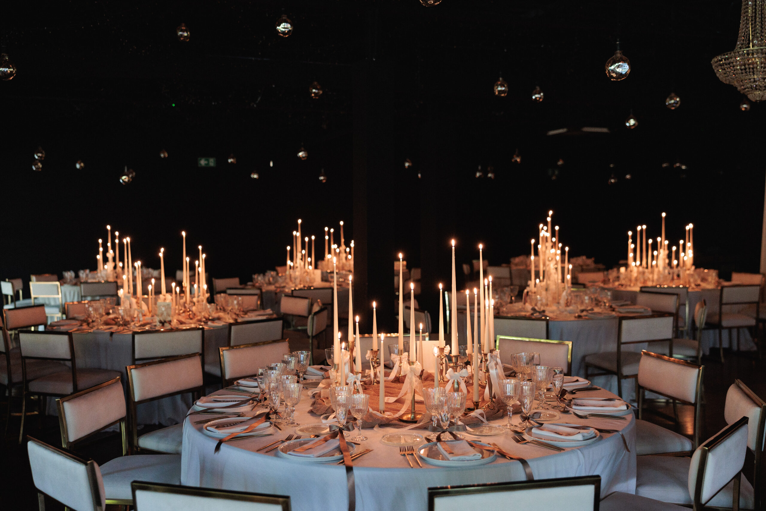 Montaje de evento con alquiler de velas largas, candelabros dorados y decoración con lazos.