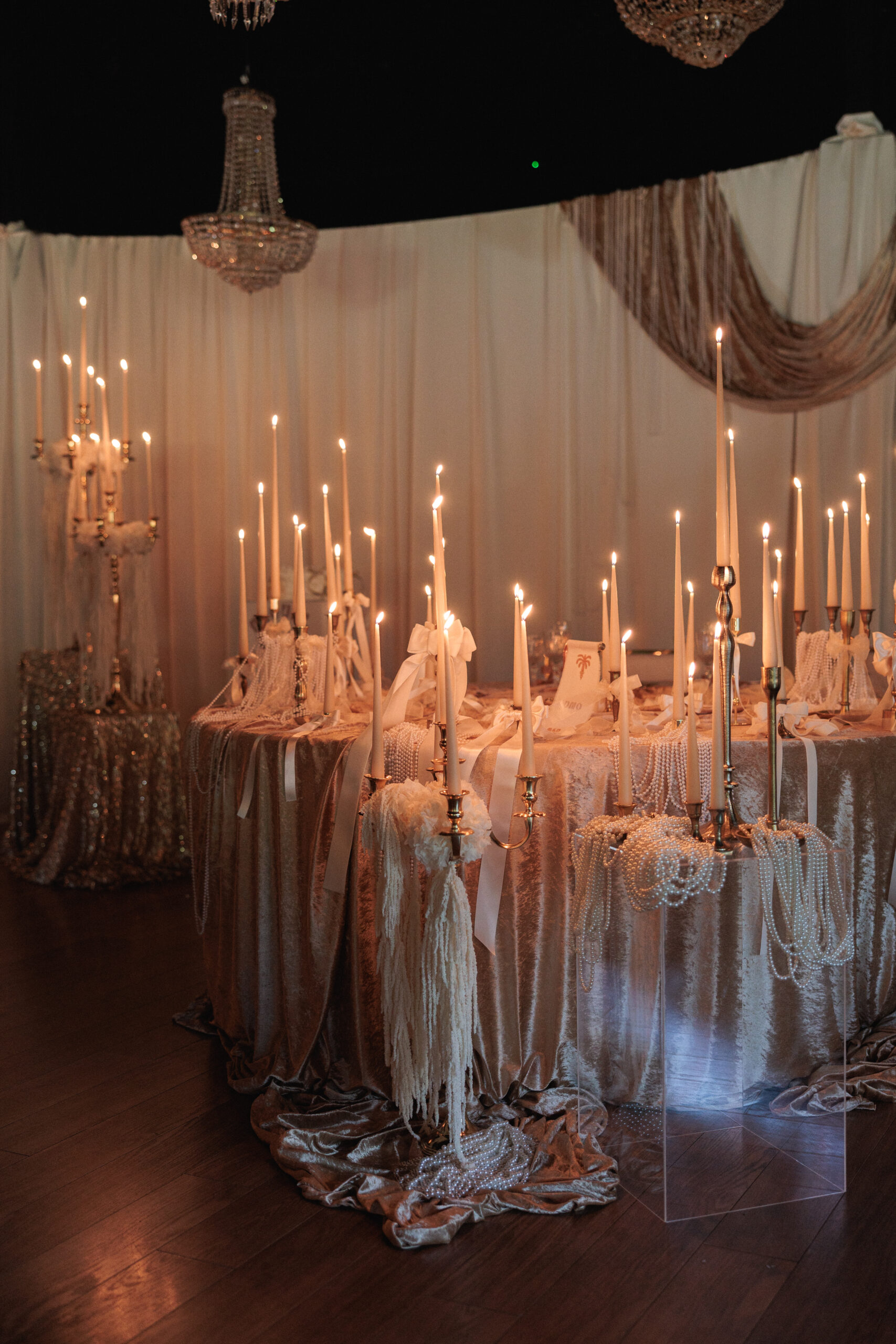 Montaje de evento con alquiler de velas largas, candelabros dorados y decoración con lazos.