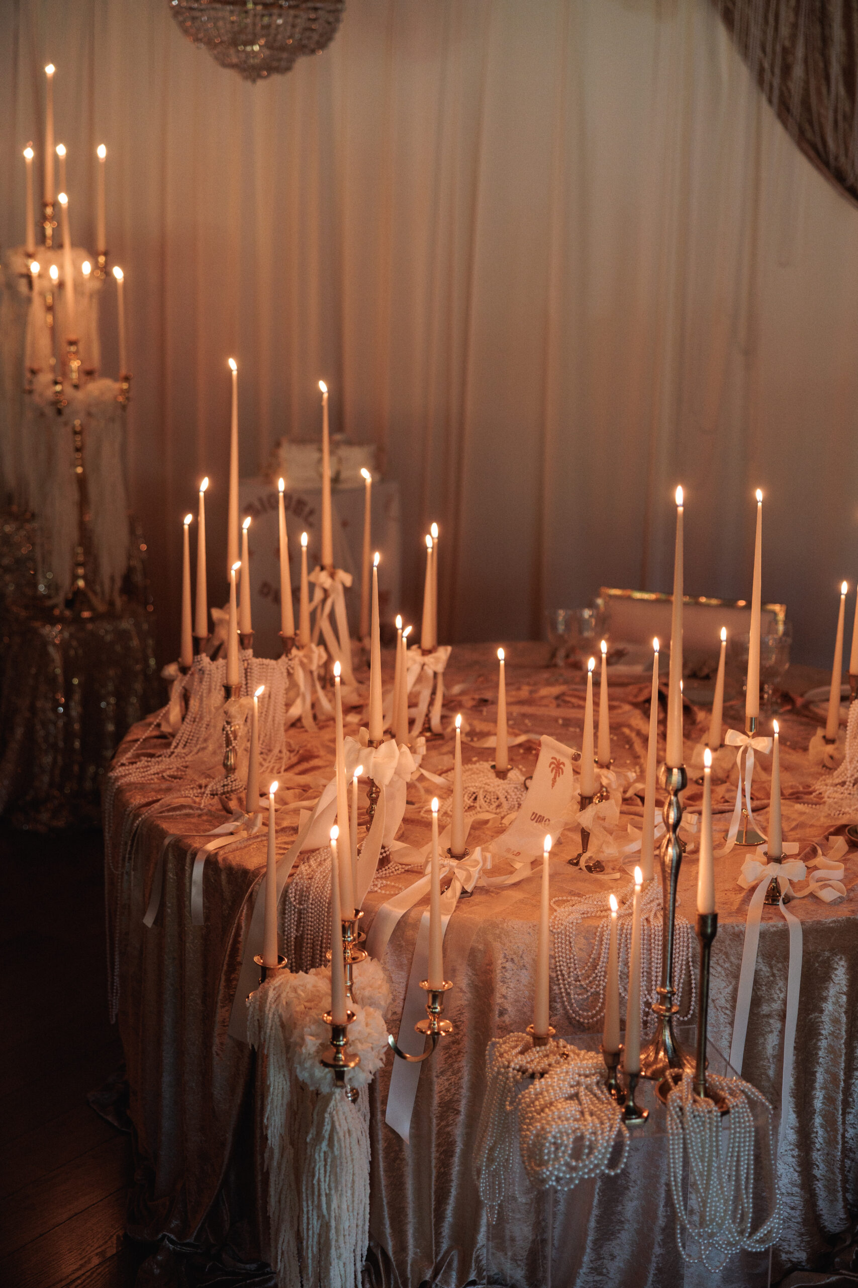 Montaje de evento con alquiler de velas largas, candelabros dorados y decoración con lazos.