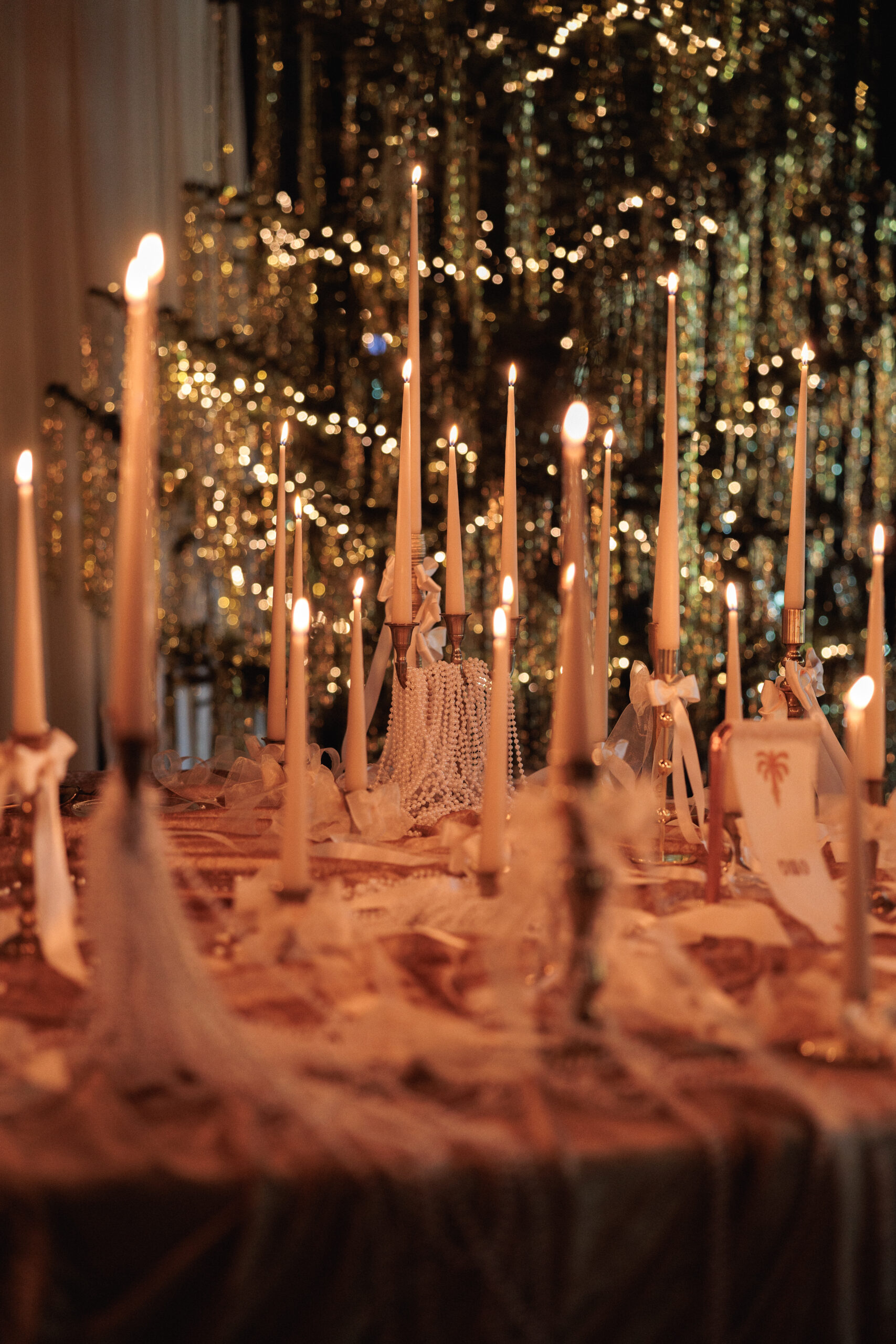 Montaje de evento con alquiler de velas largas, candelabros dorados y decoración con lazos.