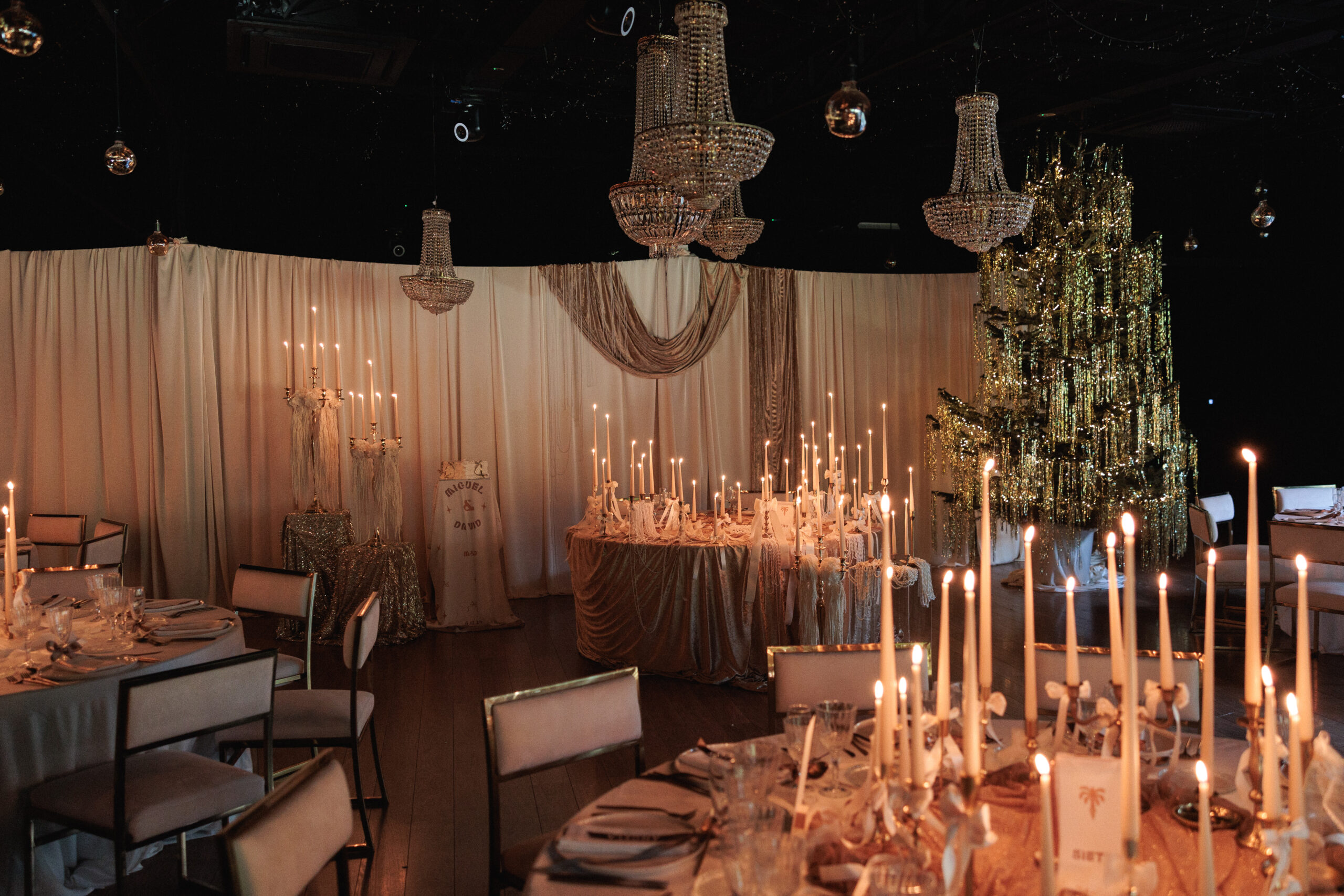Montaje de evento con alquiler de velas largas, candelabros dorados y decoración con lazos.