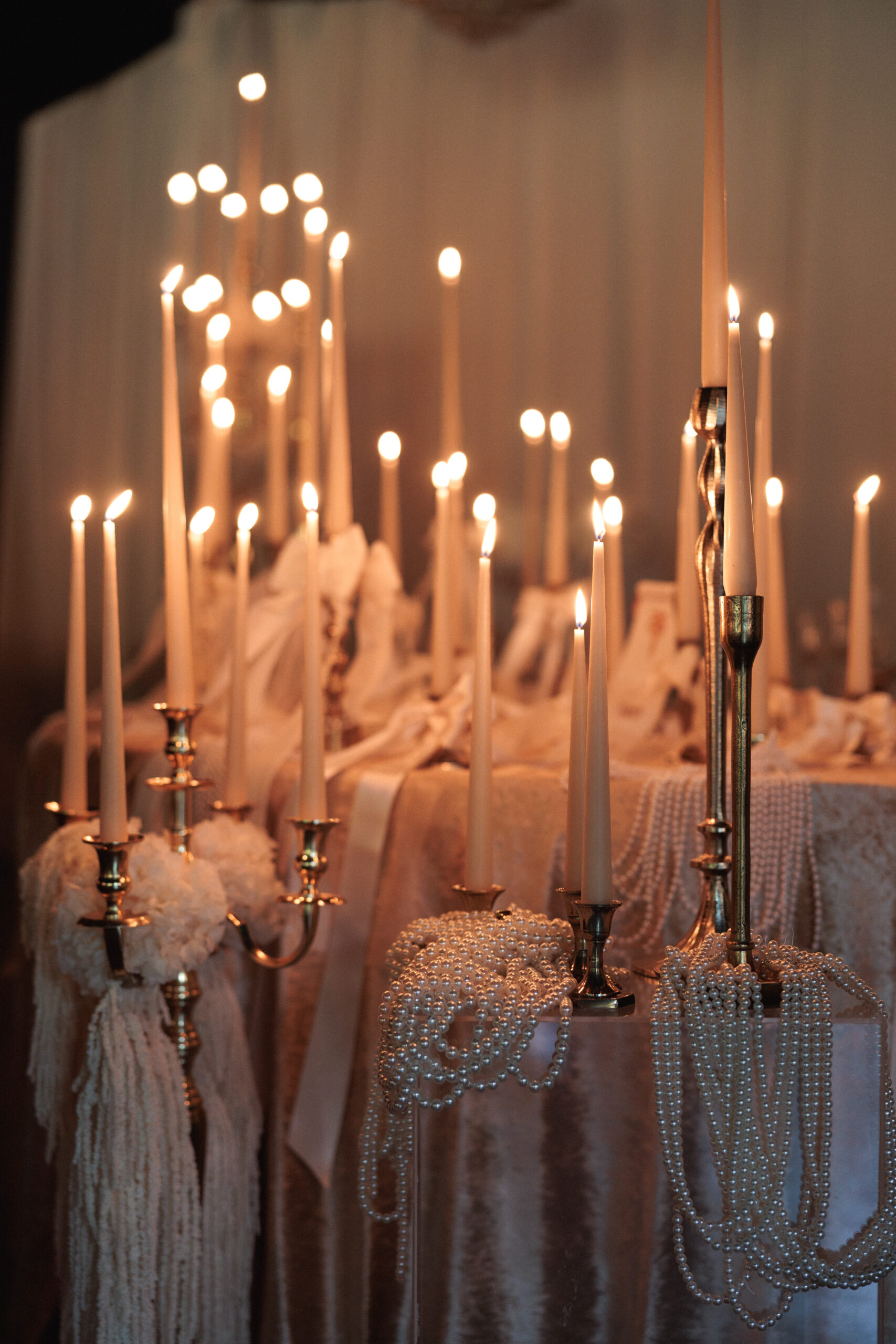 Montaje de evento con alquiler de velas largas, candelabros dorados y decoración con lazos.