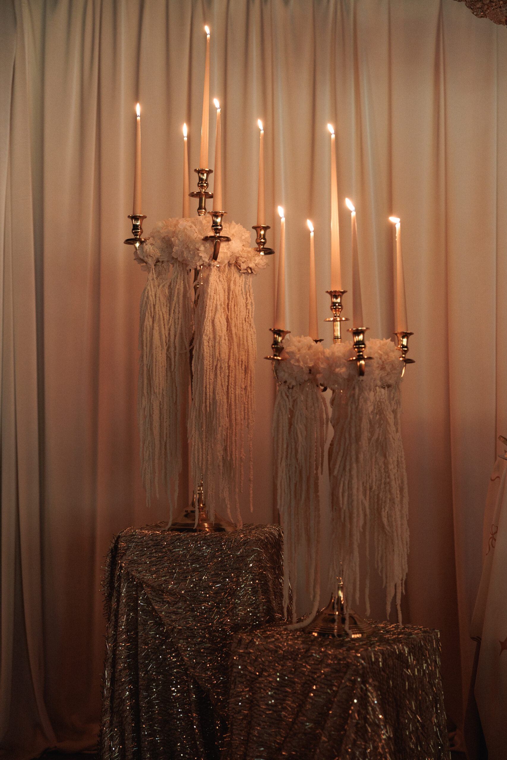 Montaje de evento con alquiler de velas largas, candelabros dorados y decoración con lazos.