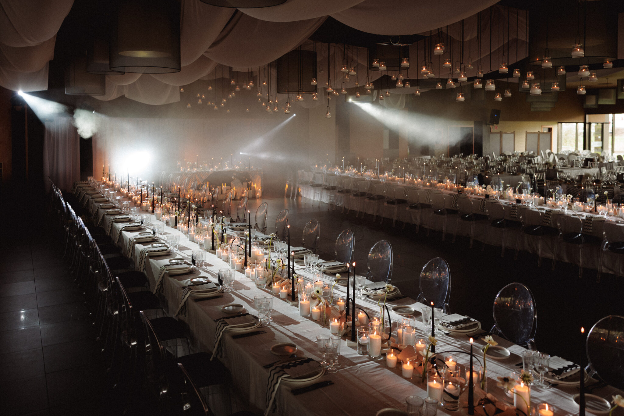 Decoración de mesa de boda con velas blancas y candelabros negros en un salón de eventos elegante