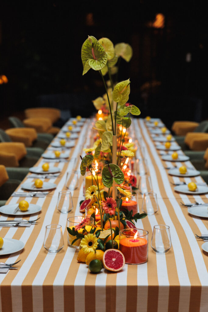 Decoración de evento en Uppery Club Málaga con mesa larga, velas encendidas, cítricos frescos y flores en tonos cálidos