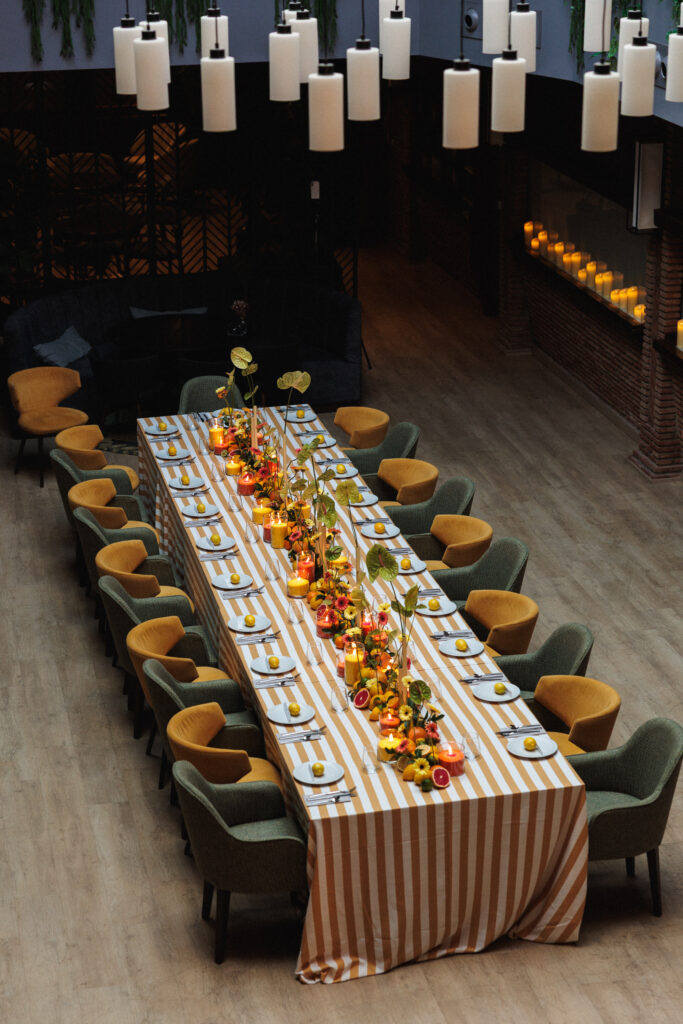 Decoración de evento en Uppery Club Málaga con mesa larga, velas encendidas, cítricos frescos y flores en tonos cálidos