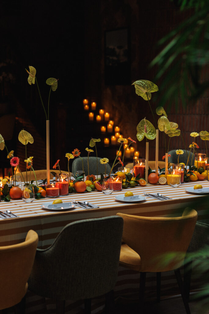 Decoración de evento en Uppery Club Málaga con mesa larga, velas encendidas, cítricos frescos y flores en tonos cálidos