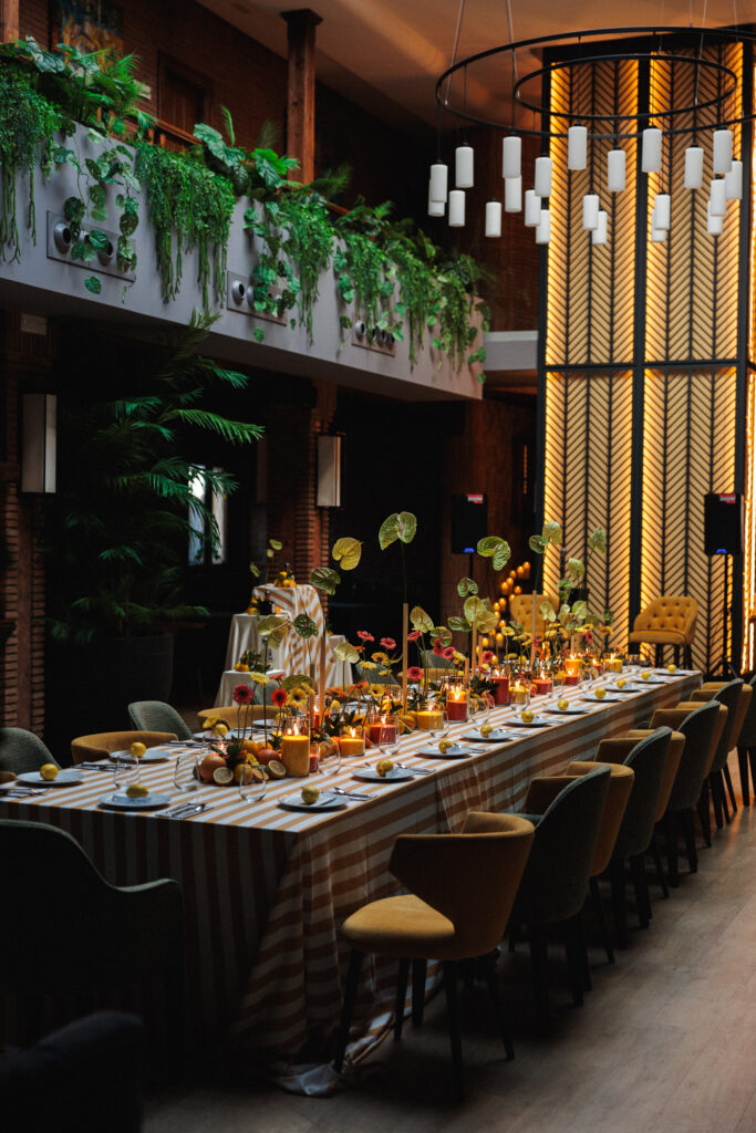 Decoración de evento en Uppery Club Málaga con mesa larga, velas encendidas, cítricos frescos y flores en tonos cálidos