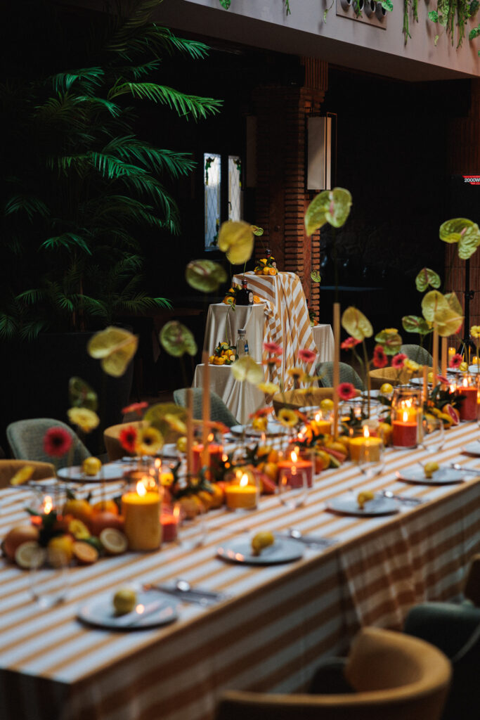 Decoración de evento en Uppery Club Málaga con mesa larga, velas encendidas, cítricos frescos y flores en tonos cálidos