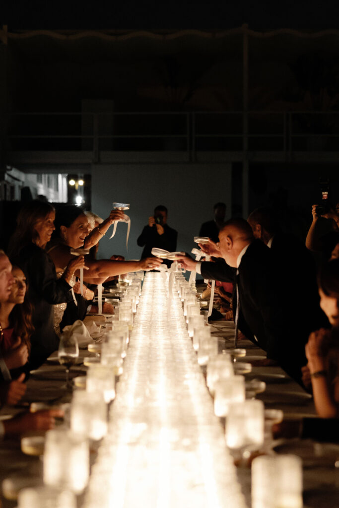 Decoración de evento en Lamarr Alicante con largas mesas iluminadas por cientos de velas blancas, diseño elegante junto a palmeras