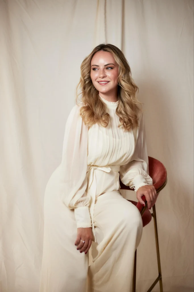 Retrato de Michelle Brown, fundadora de Candles by Angelina, con vestido blanco y fondo neutro.