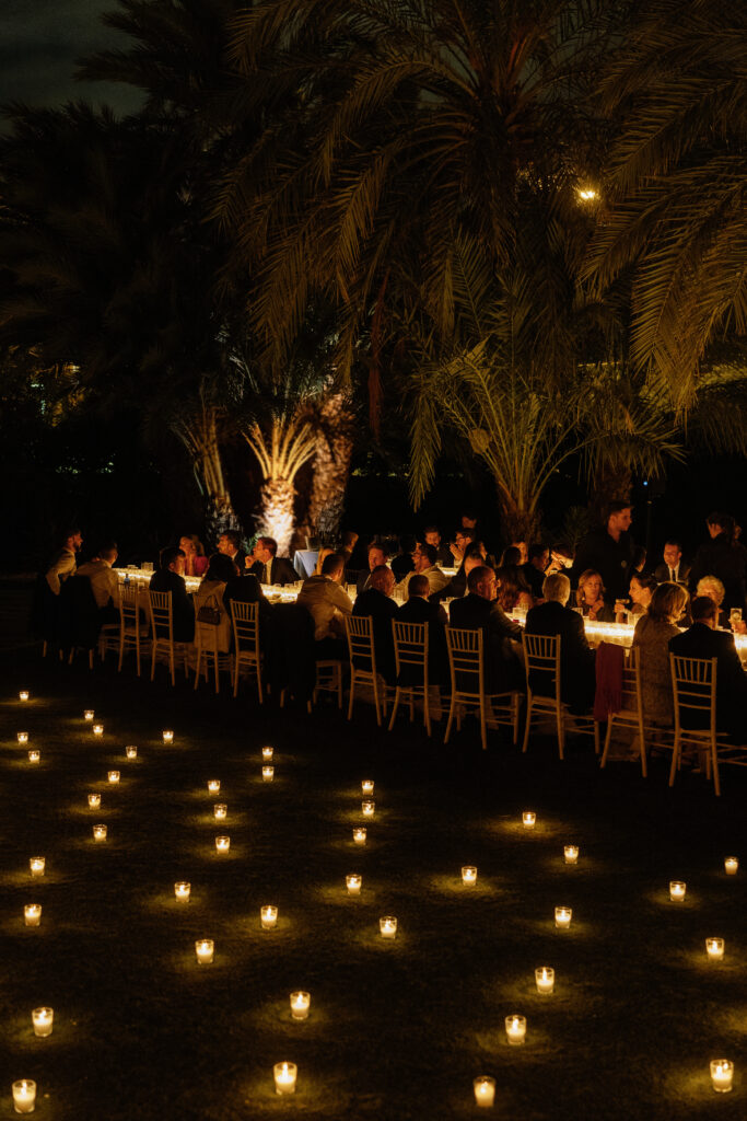 Decoración de evento en Lamarr Alicante con largas mesas iluminadas por cientos de velas blancas, diseño elegante junto a palmeras